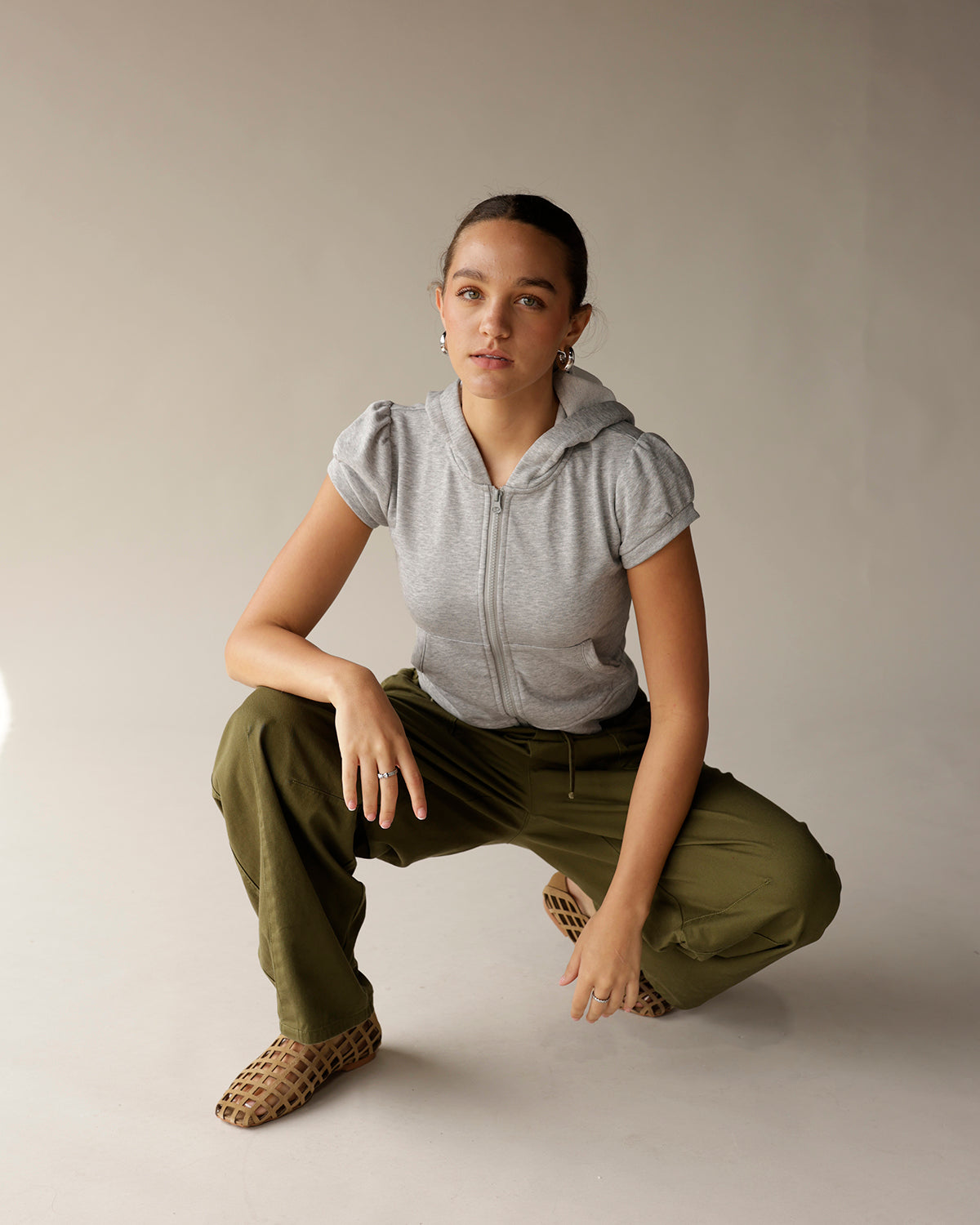 Olive green cargo barrel pants with drawstring waist, worn with gray zip hoodie