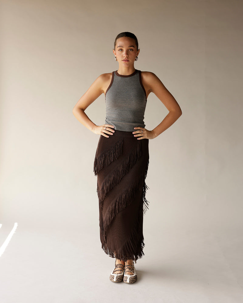Dark brown fringe midi skirt with diagonal layered fringe detail, worn with gray tank top