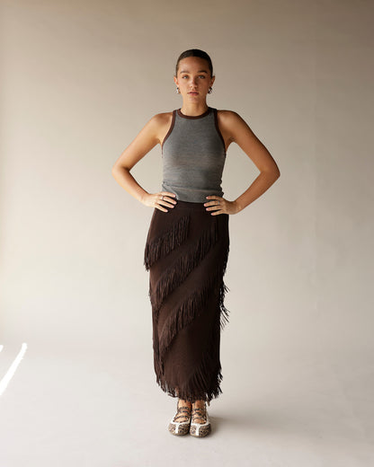 Dark brown fringe midi skirt with diagonal layered fringe detail, worn with gray tank top