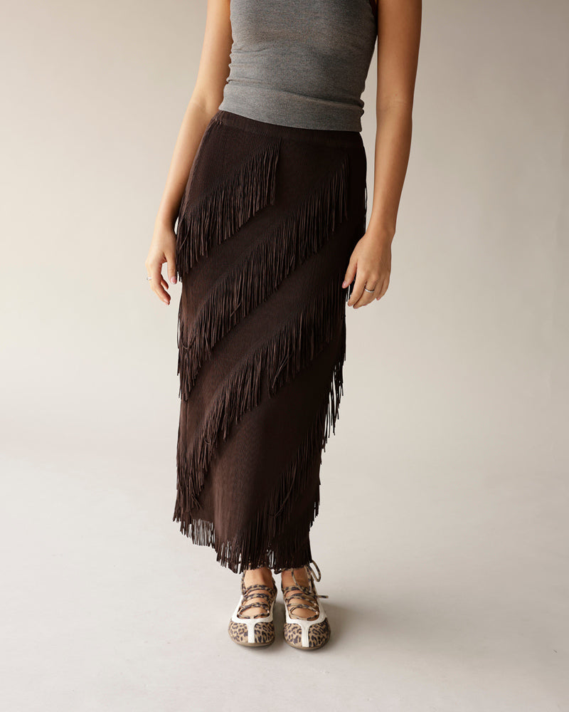 Dark brown diagonal fringe maxi skirt paired with gray tank top and leopard flats