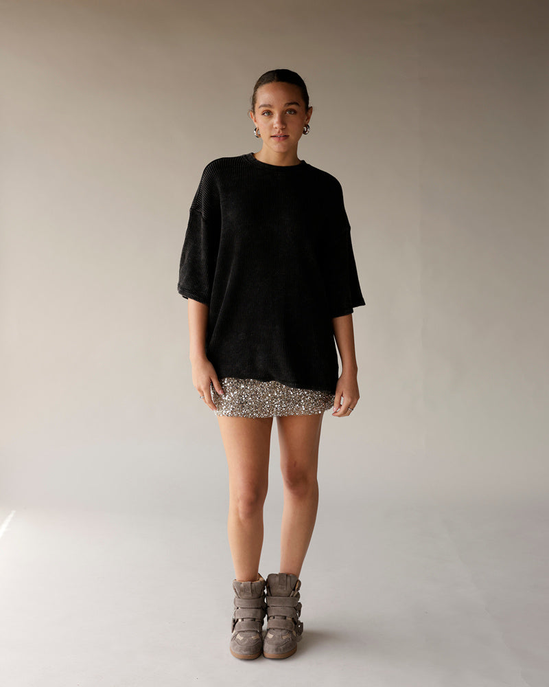 Oversized black ribbed short-sleeve tee styled with a silver sequin mini skirt