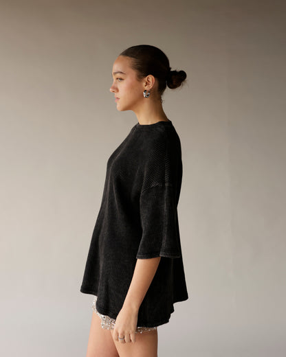 Oversized black ribbed short-sleeve tee with relaxed silhouette, worn with sequin shorts