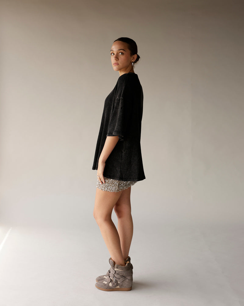 Black ribbed oversized short-sleeve tee styled with sequin mini skirt and wedge sneakers