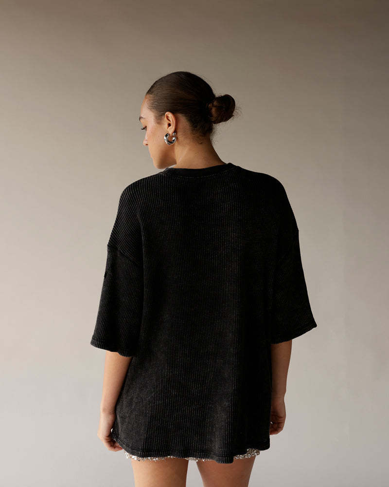 Black oversized ribbed short-sleeve tee shown from the back on a female model.