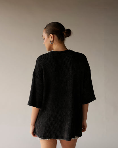 Black oversized ribbed short-sleeve tee shown from the back on a female model.