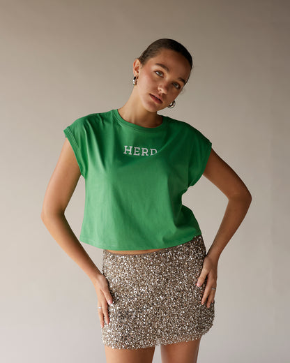 Custom kelly green muscle tee with HERD graphic, worn with sequin mini skirt