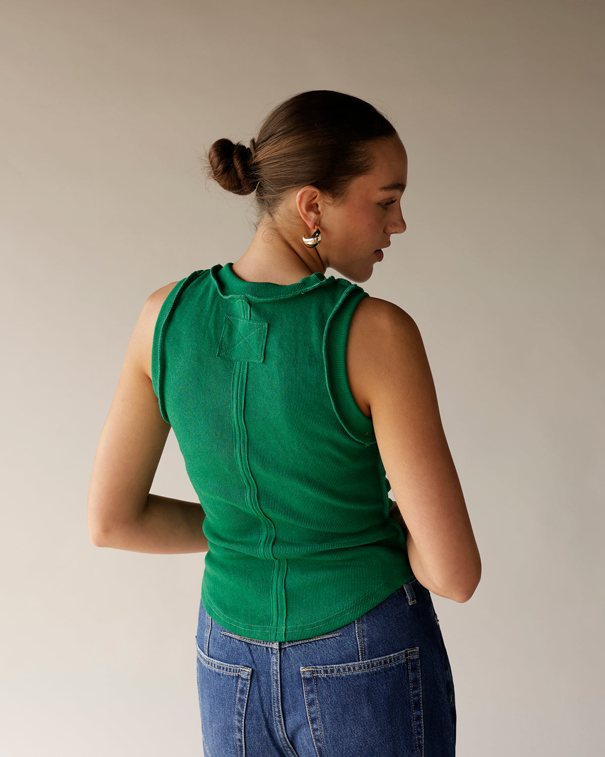 Green ribbed sleeveless tank top with back seam detail, worn with blue jeans