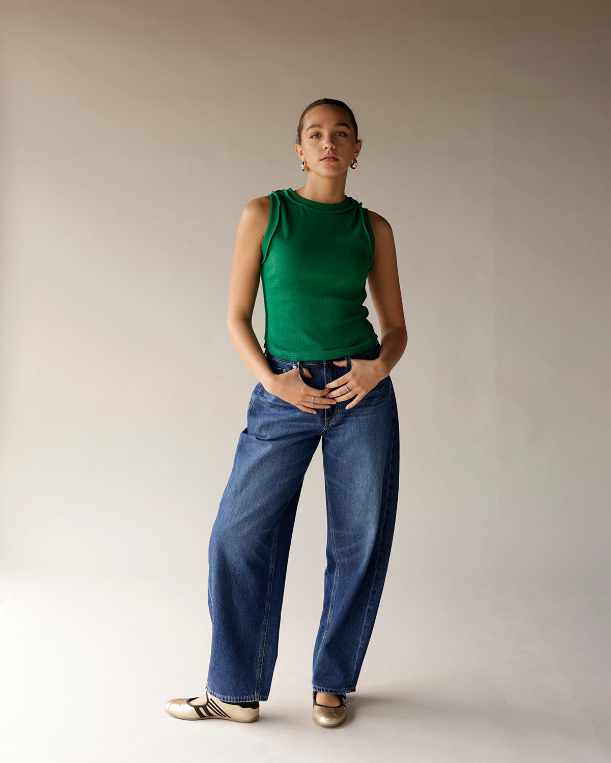 Green ribbed sleeveless tank top with mock neck, worn with wide-leg jeans