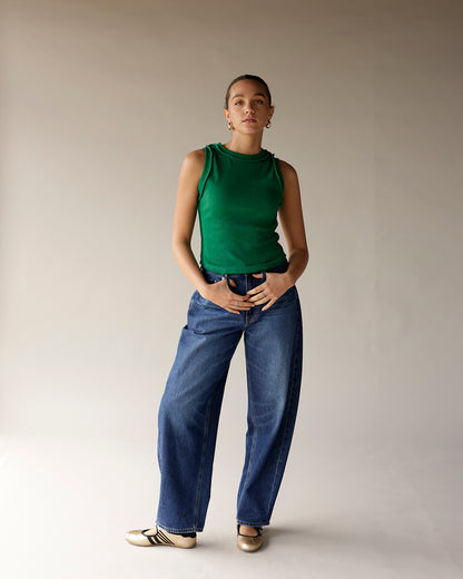 Green ribbed sleeveless tank top with mock neck, worn with wide-leg jeans