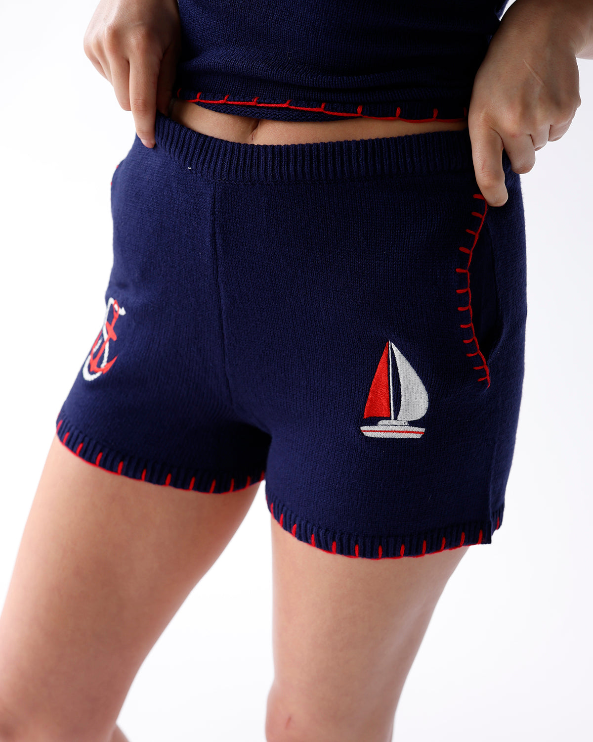 navy knit shorts with red embroidered details and anchor and sailboat patches