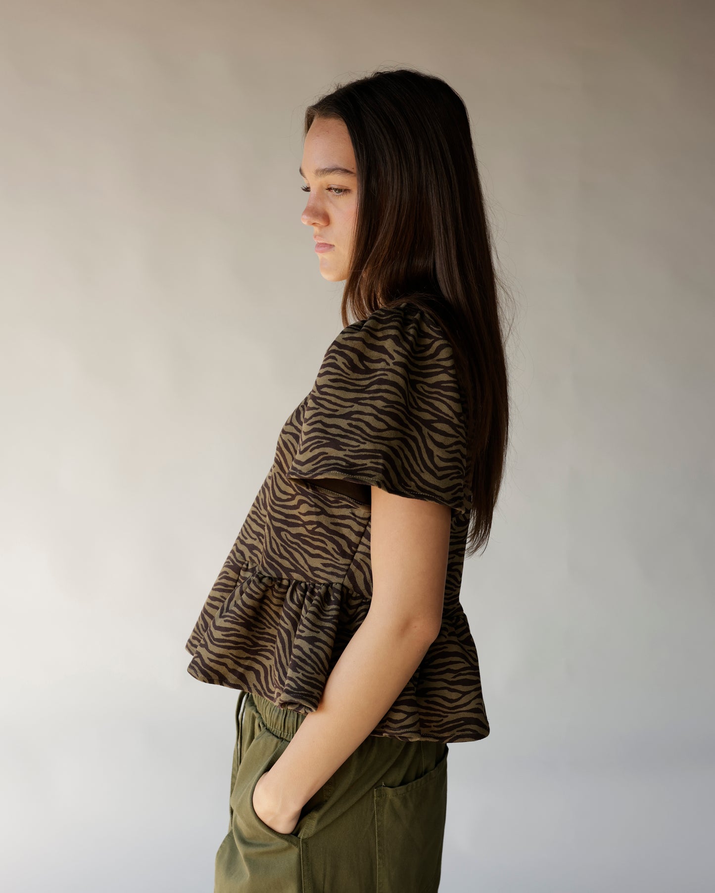 Brown and black zebra print short sleeve peplum top with cutout waist detail.