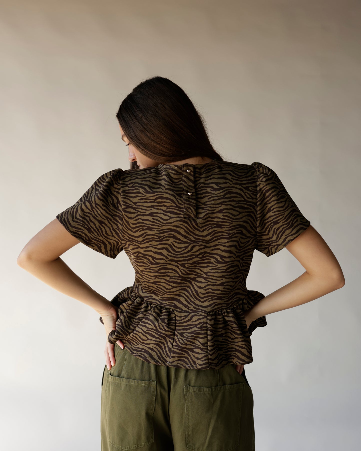 Brown and black zebra print peplum top with short sleeves and back button detail