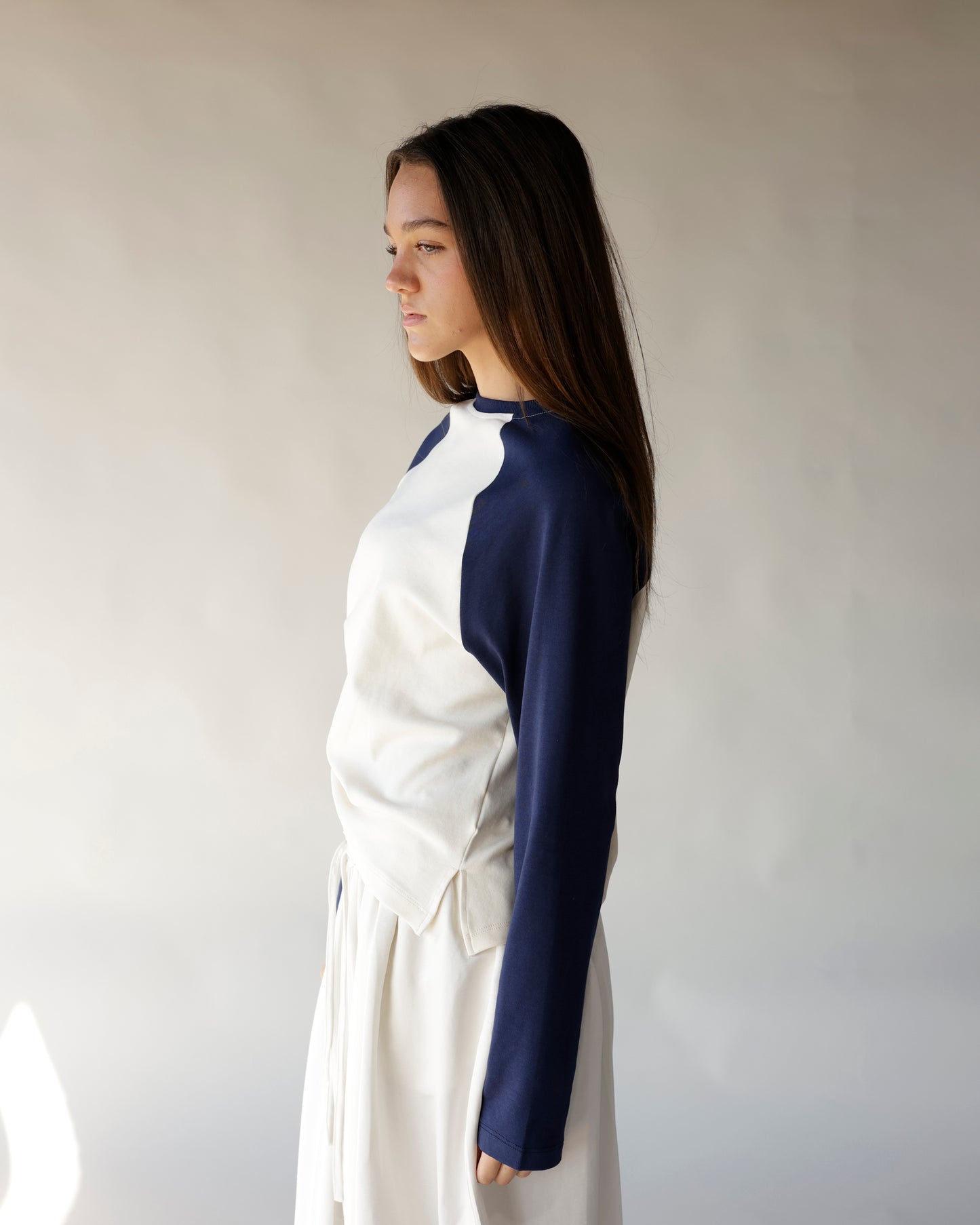 Navy and cream raglan long-sleeve top with color-block design, side profile view.