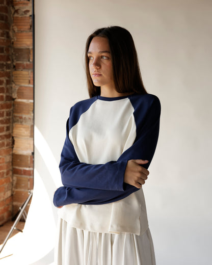 Navy and cream raglan sweatshirt with blue sleeves, paired with a white midi skirt.
