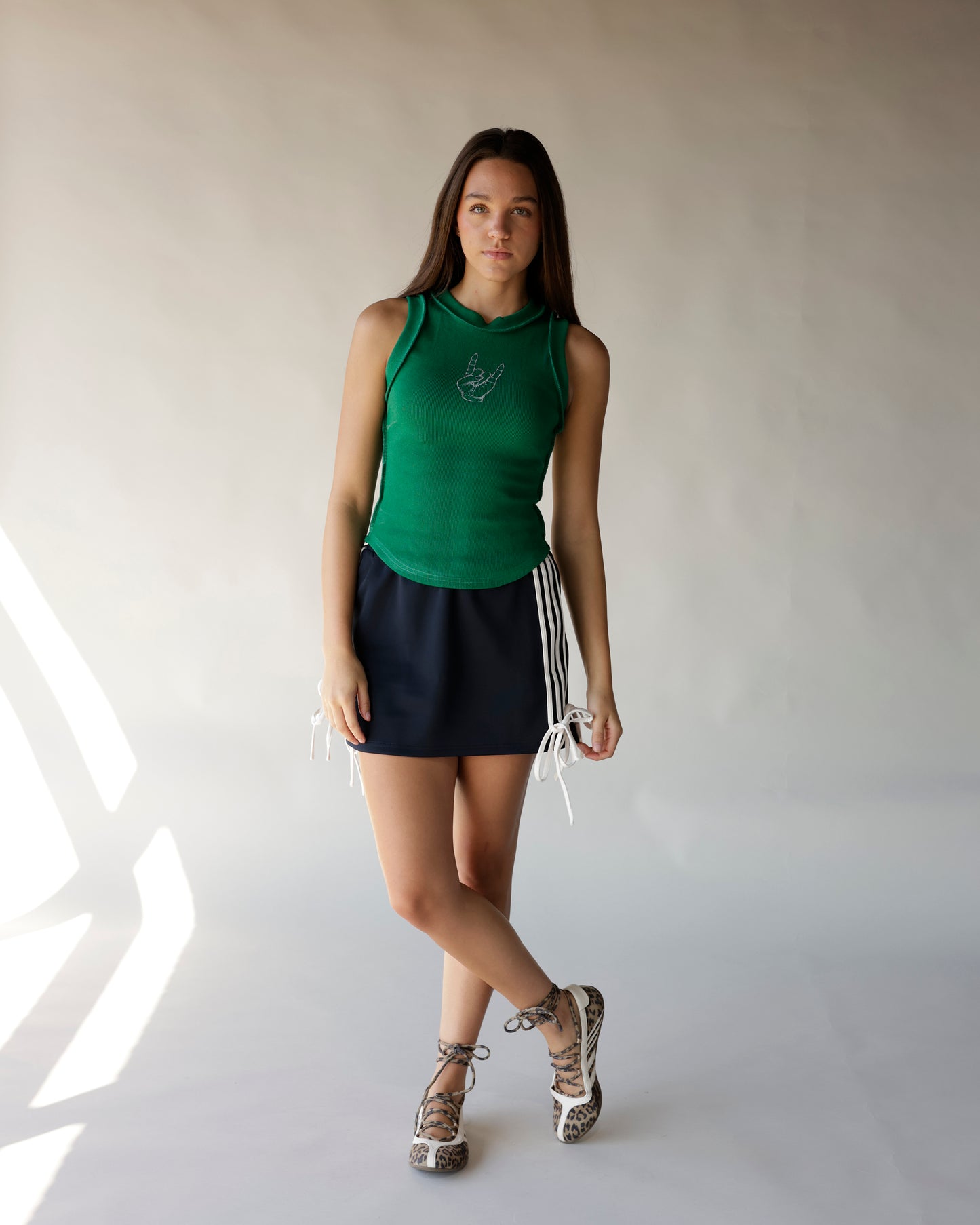 Black mini skirt with white stripe trim and tie details, styled with green tank top