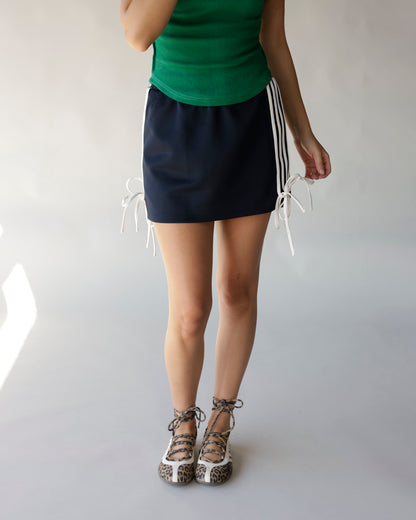 Black mini track skirt with white side stripe ties, paired with green top