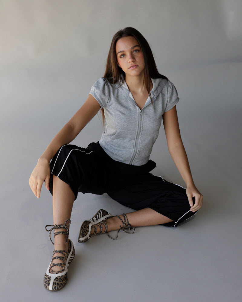 Black windbreaker pants with white side stripes, worn by seated female model