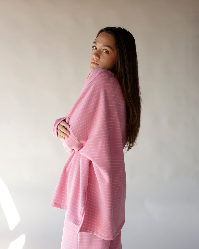 Oversized pink striped long sleeve tee worn by model, side profile view