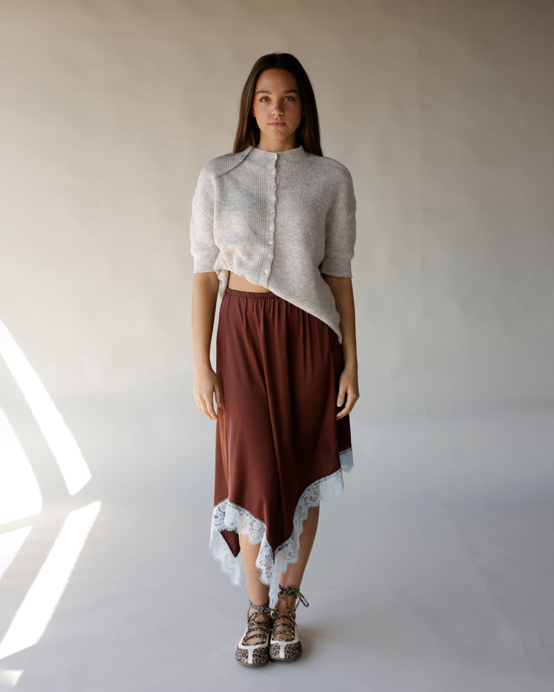 Gray short-sleeve ribbed knit cardigan with small buttons, worn with brown lace-trim skirt