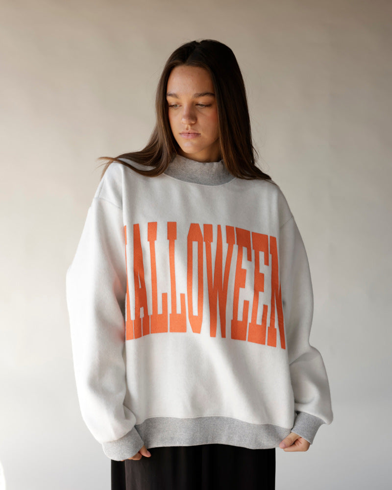 White oversized reversible mock neck sweatshirt with bold orange HALLOWEEN graphic print
