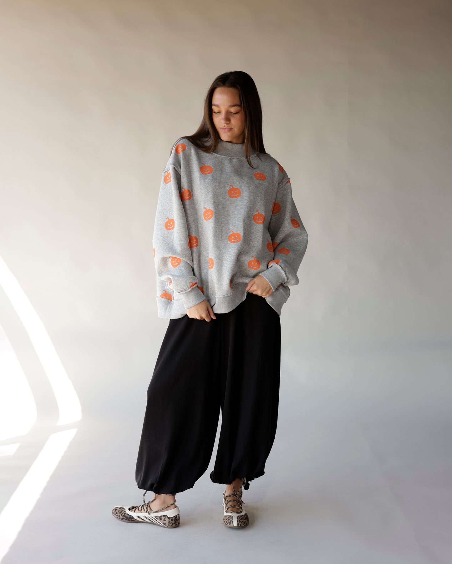 Gray oversized mock neck sweatshirt with orange jack-o-lantern pumpkin print pattern