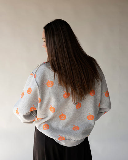 Gray crewneck sweatshirt with all-over orange jack-o-lantern pumpkin print, back view