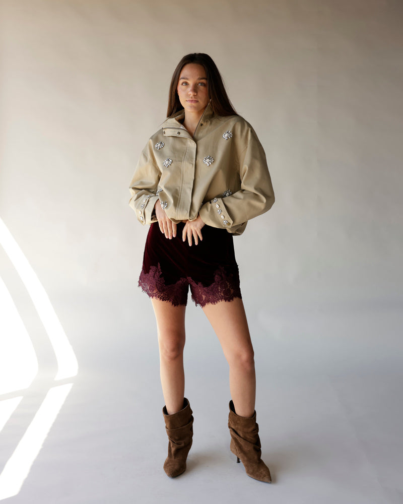 Maroon velvet shorts with scalloped lace hem trim, worn with beige jacket