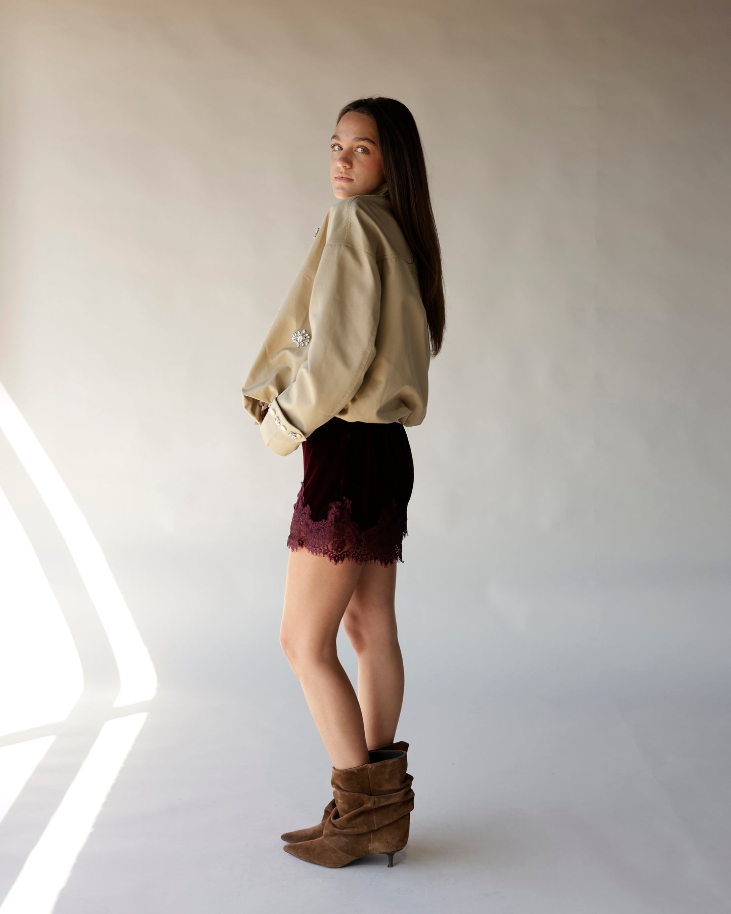 Maroon velvet mini shorts with lace hem detail, worn with tan jacket and brown boots