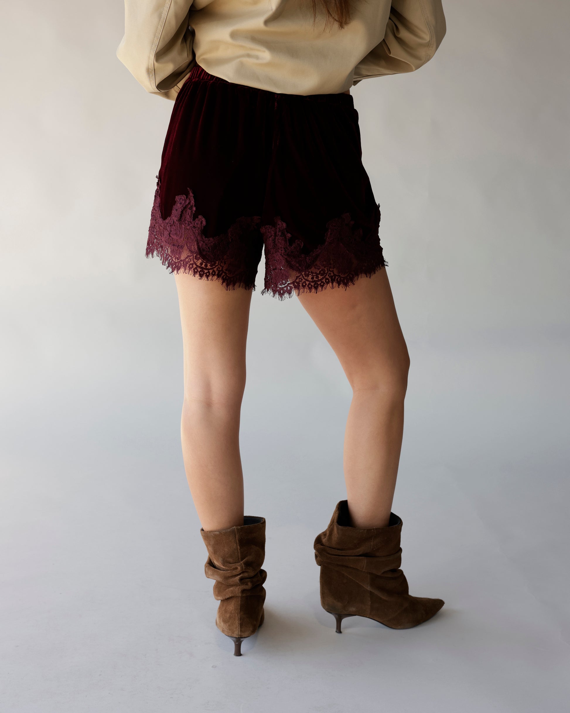 Maroon velvet shorts with lace hem trim, back view, styled with brown suede boots