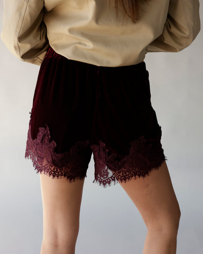 Maroon velvet shorts with intricate lace trim hem, elastic waist, back view