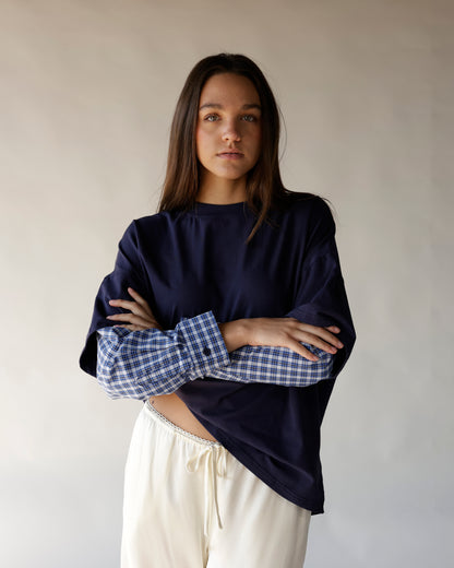 Oversized navy tee with blue plaid contrast sleeves, paired with cream drawstring pants.