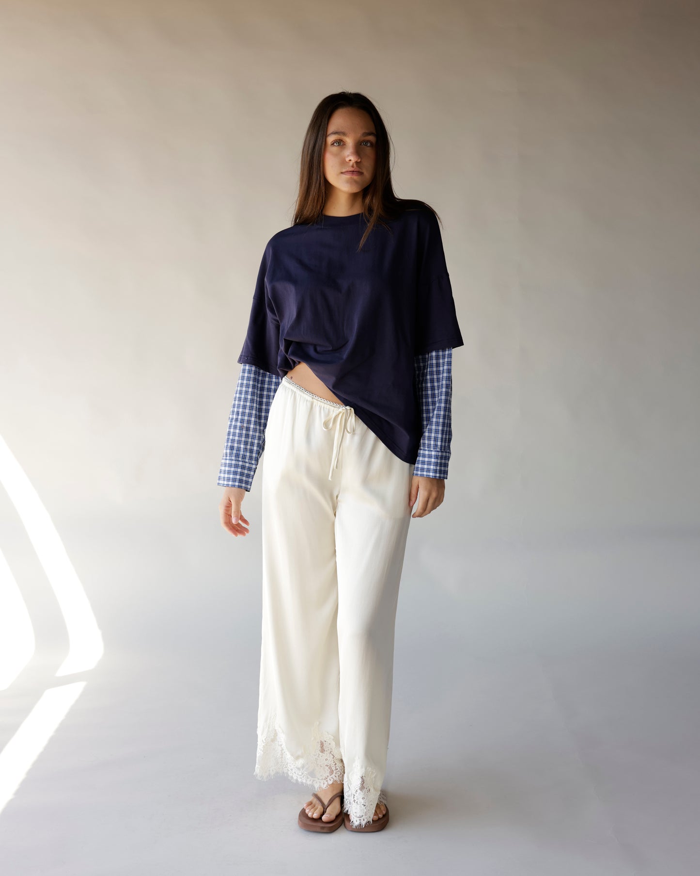 Oversized navy tee with blue plaid long sleeves, worn with cream lace-hem pants
