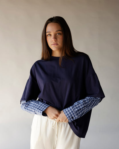 Oversized navy tee with blue plaid contrast sleeves, paired with cream drawstring pants.