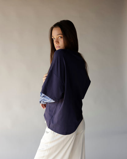 Women's navy oversized top layered over blue plaid shirt with white skirt