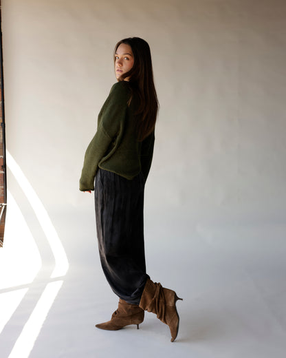 Black satin jogger pants with relaxed fit, styled with green sweater and brown boots.