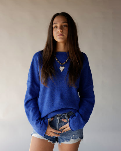 Royal blue oversized mock neck sweater styled with denim cutoff shorts and gold heart necklace.
