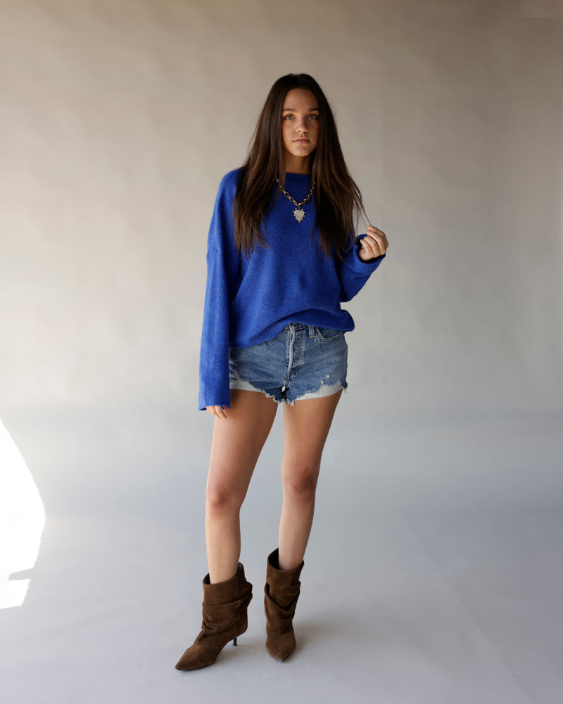 Royal blue oversized mock neck knit sweater with long sleeves, worn with denim shorts