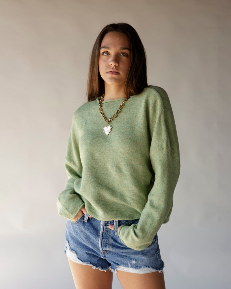 Oversized sage green knit sweater with crew neck, worn with denim cutoff shorts