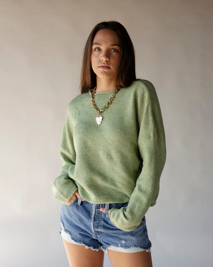 Oversized sage green knit sweater with crew neck, worn with denim cutoff shorts