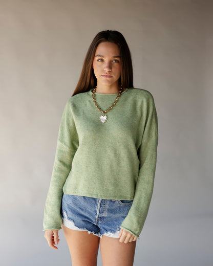 Sage green cropped crew neck sweater with long sleeves, worn with denim shorts