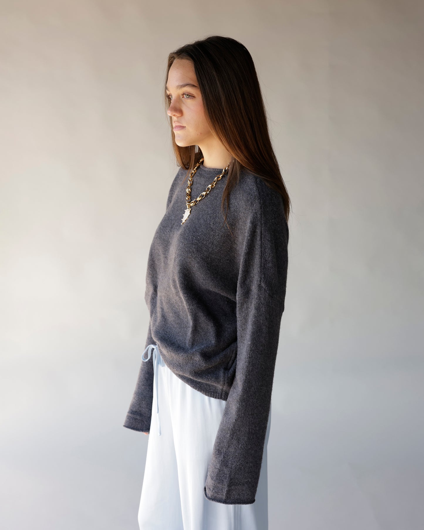 Dark gray mini mock neck cashmere sweater with long sleeves, worn with white pants