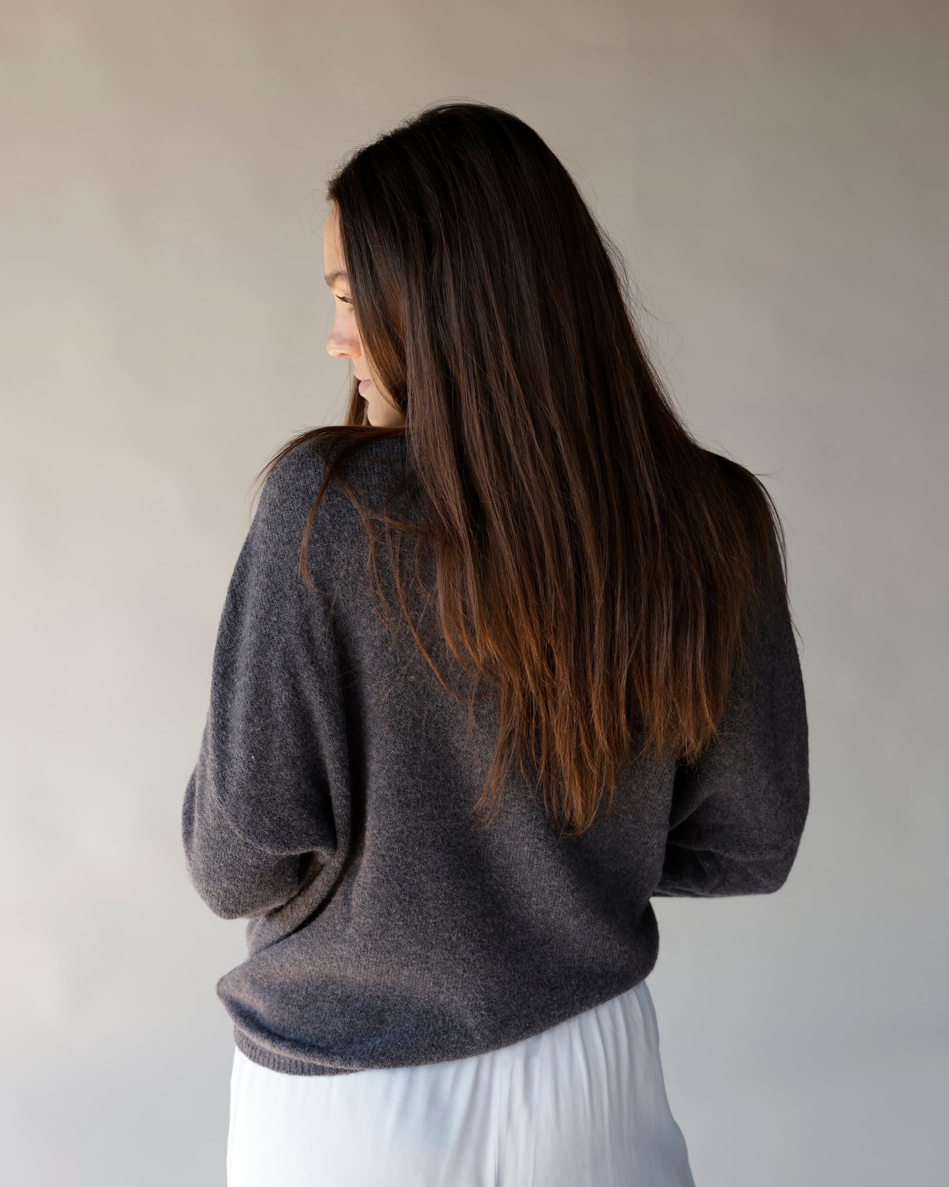 Dark gray knit mock neck sweater, relaxed fit, shown from the back on a model