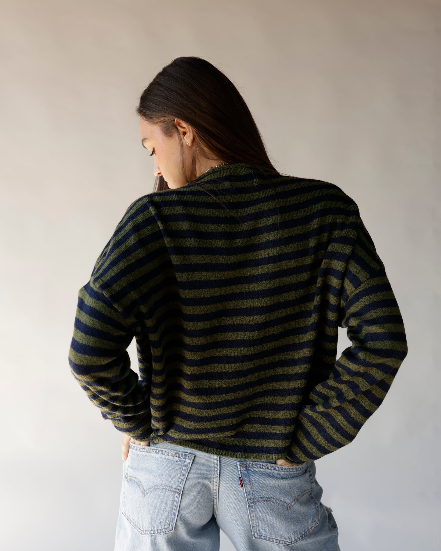 Olive and navy striped knit mock neck sweater, rear view, paired with light wash jeans.