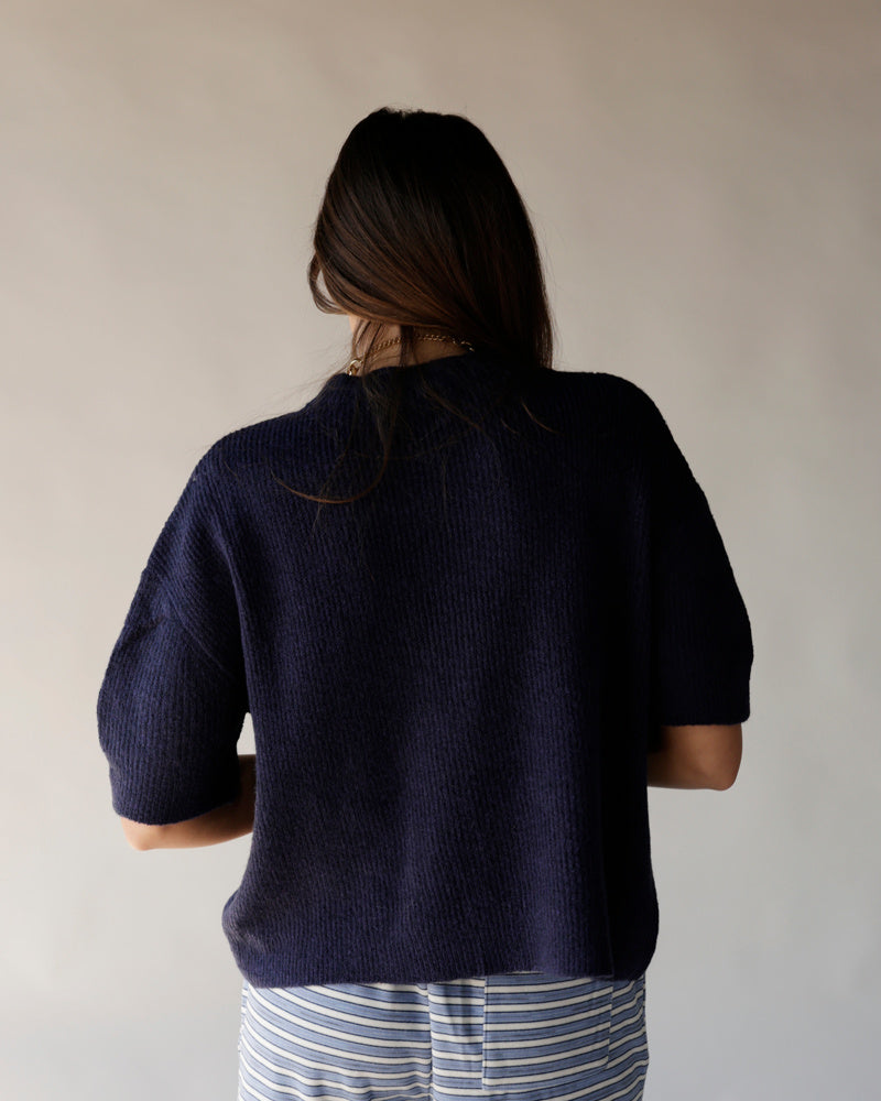 Navy blue short sleeve knit cardigan, ribbed texture, cropped fit, back view