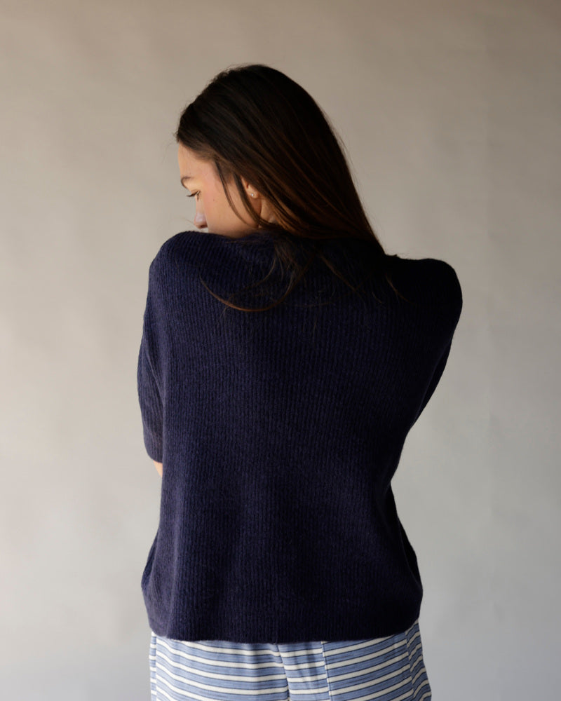Navy blue short sleeve knit cardigan, ribbed texture, worn from the back view