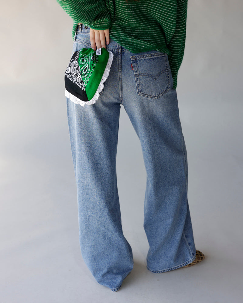 Green and black paisley bandana bag with white ruffled hem, held at hip