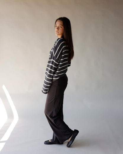 Dark gray striped knit sweater with white horizontal stripes, worn with black wide-leg trousers