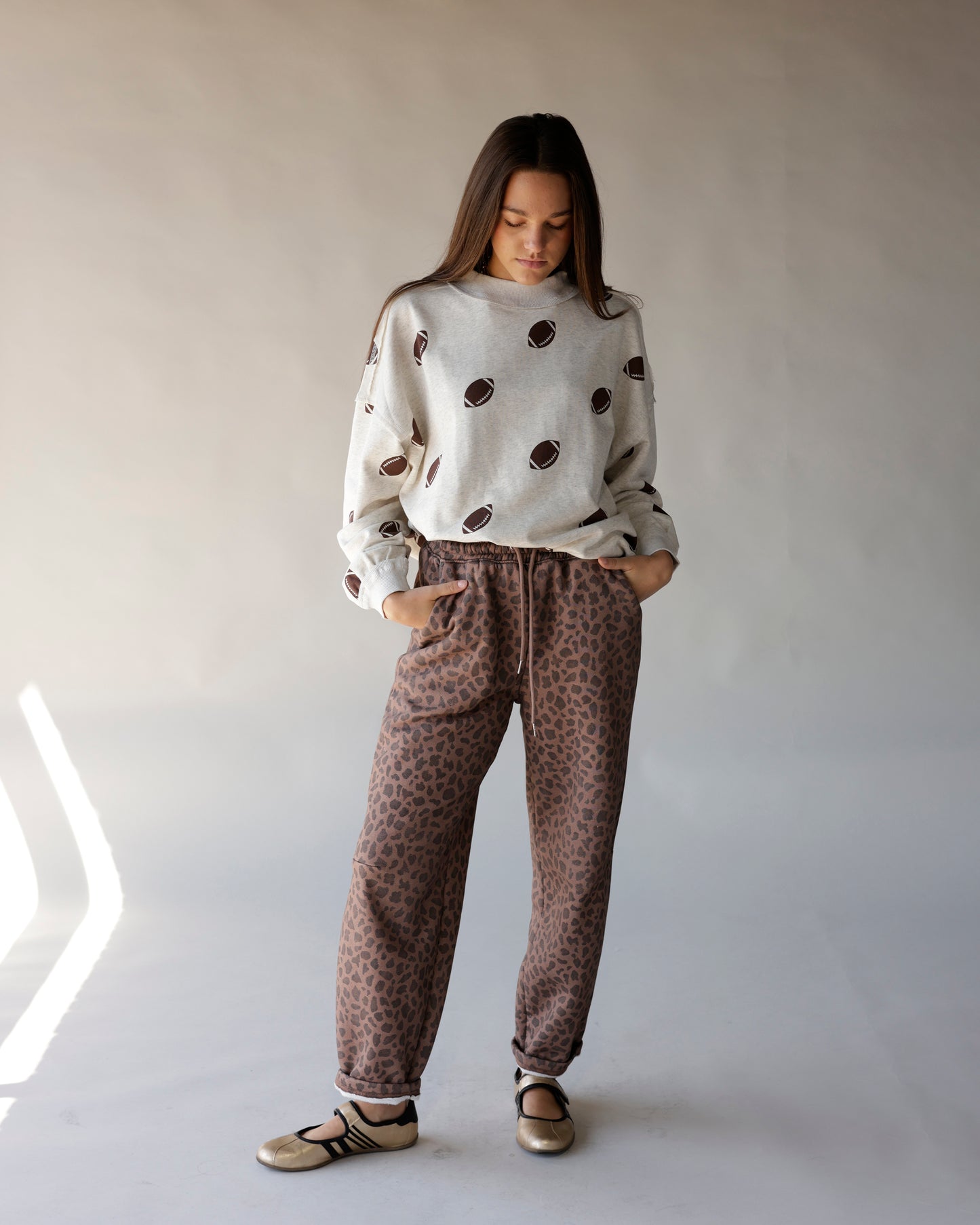 Cream mock neck sweatshirt with allover brown football print, relaxed fit