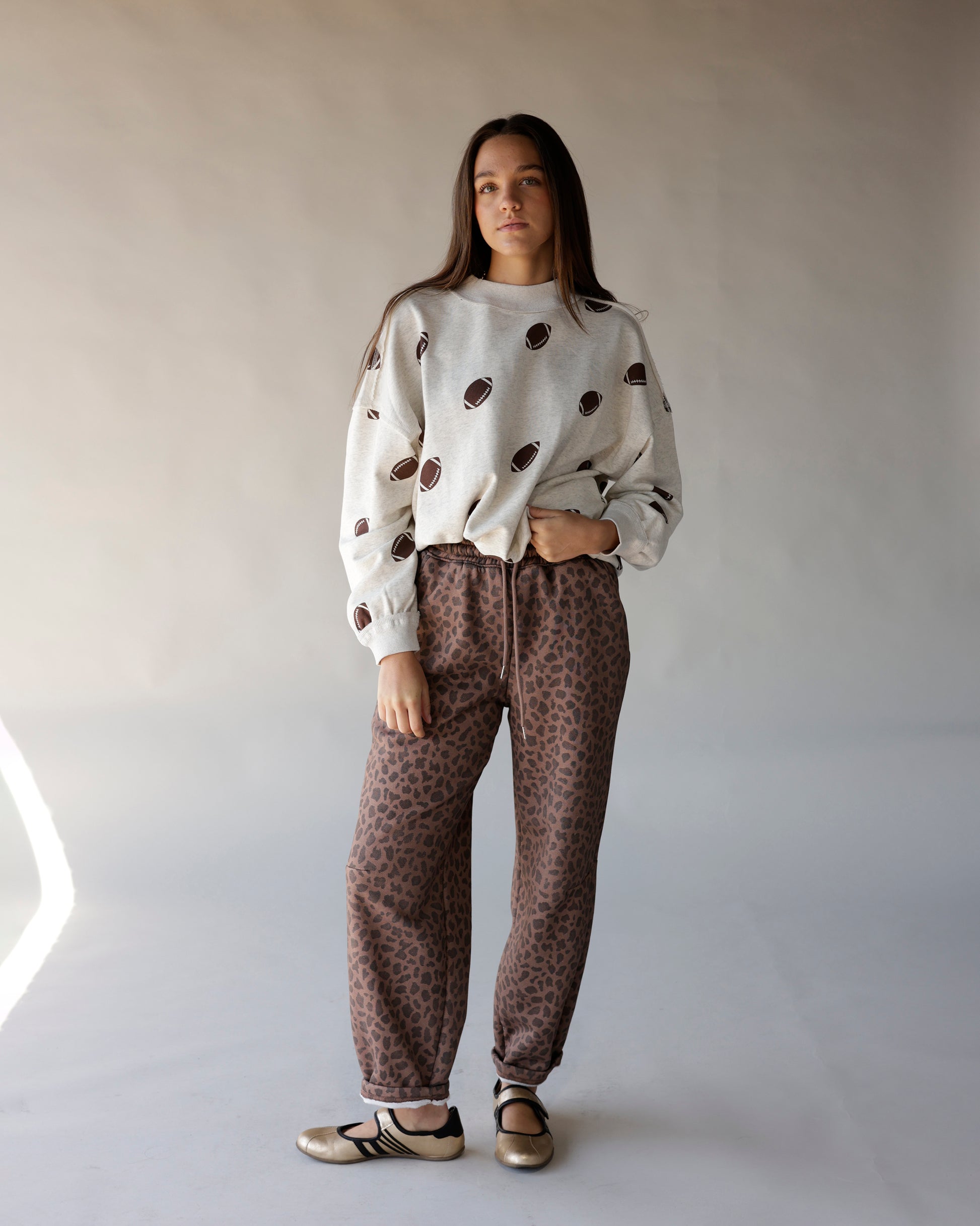 Cream mock neck sweatshirt with allover brown football print, worn with leopard joggers