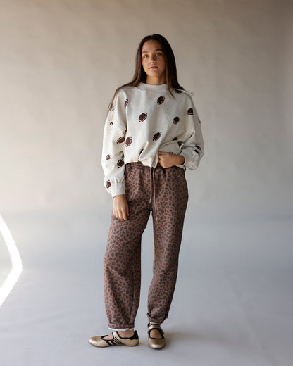 Cream mock neck sweatshirt with allover brown football print, worn with leopard joggers